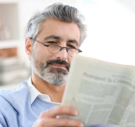 Mann mit Brille liest Zeitung. 